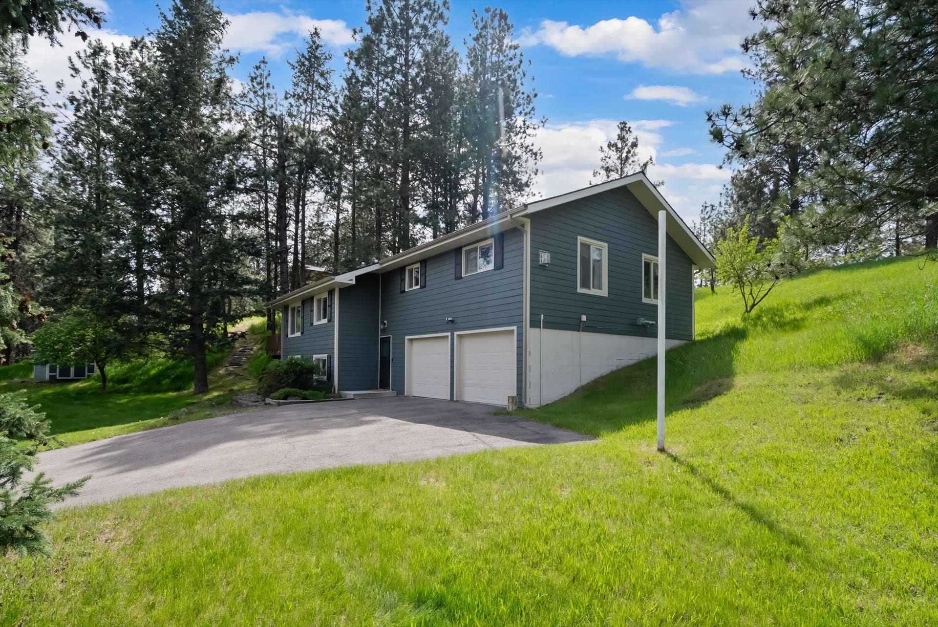 300 Peaceful Drive, Bigfork, MT 59911 Two-story residence featuring a two-car garage with white doors, dark siding, and white window trim