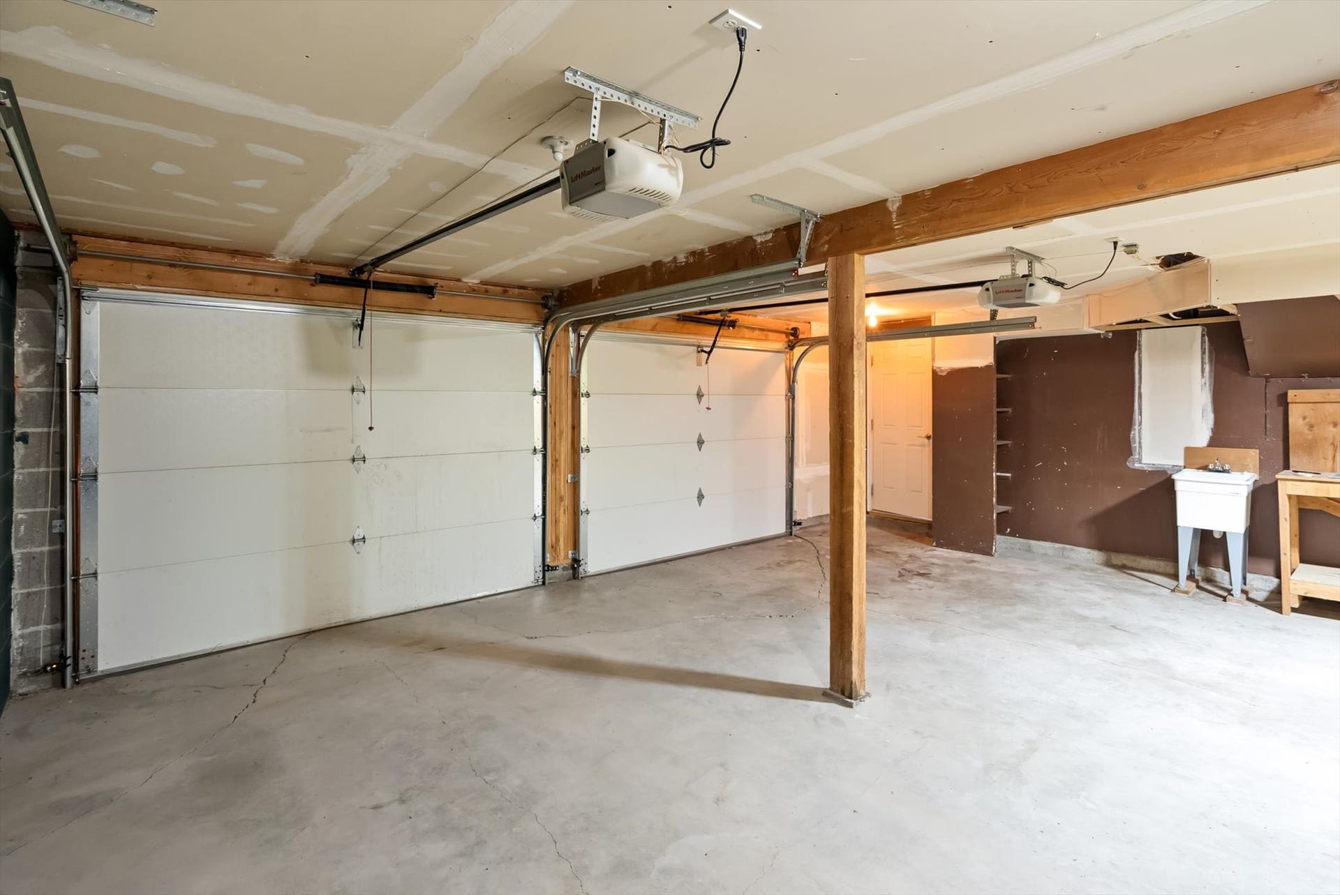 300 Peaceful Drive, Bigfork, MT 59911 Two garage door bays with automatic openers, concrete flooring, exposed wood beam construction, and built-in utility sink