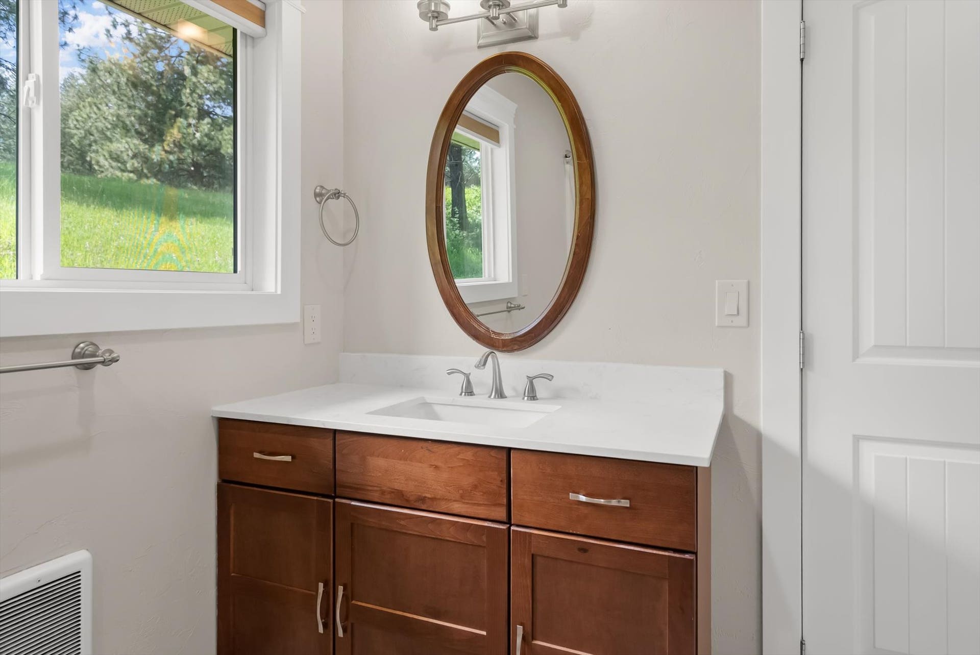 300 Peaceful Drive, Bigfork, MT 59911 Bathroom vanity featuring a wood-finish cabinet, white countertop, and an oval mirror
