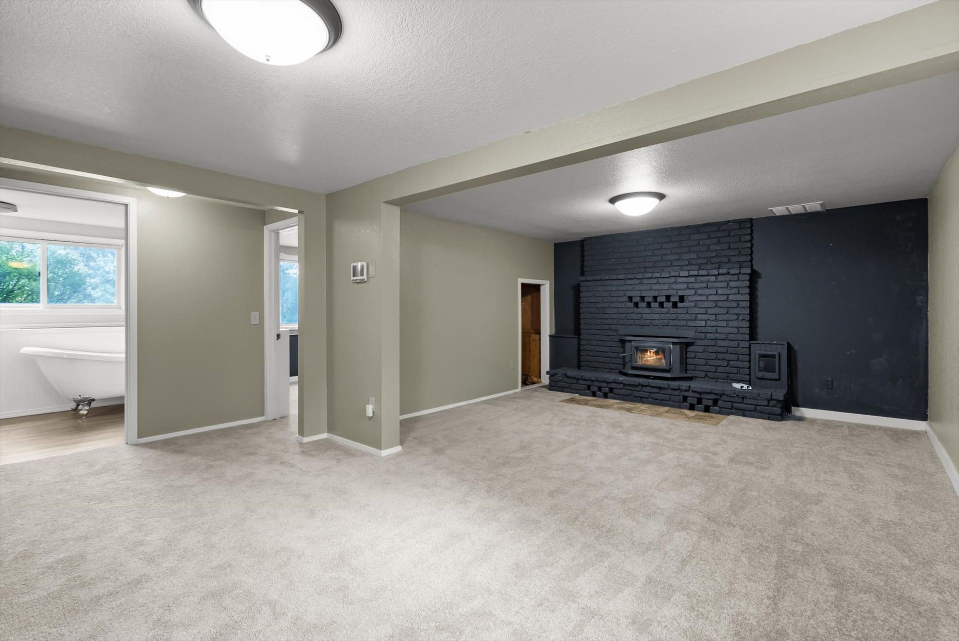 300 Peaceful Drive, Bigfork, MT 59911 Spacious room featuring light-colored carpeting, a black painted brick fireplace with a wood-burning stove insert, and neutral wall tones
