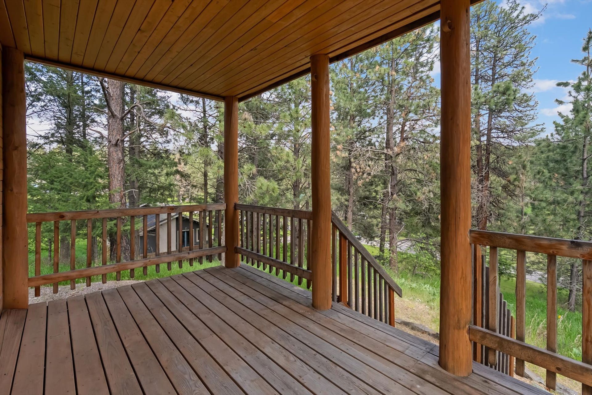 300 Peaceful Drive, Bigfork, MT 59911 Expansive covered porch featuring a natural wood ceiling, wood-finish flooring, and sturdy log supports