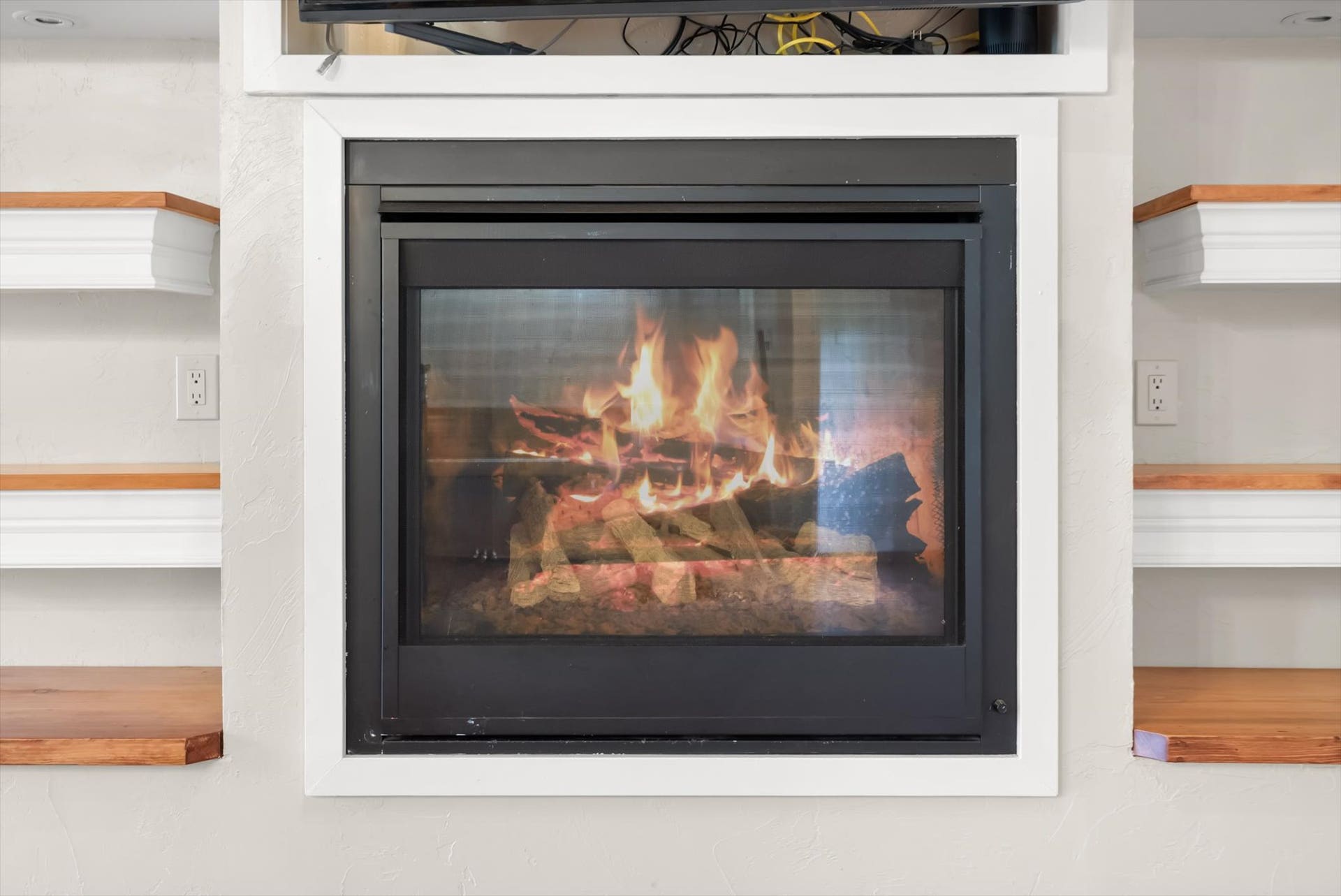 300 Peaceful Drive, Bigfork, MT 59911 Built-in fireplace with a black framed glass enclosure, flanked by custom shelving featuring white bases and wood-finish tops