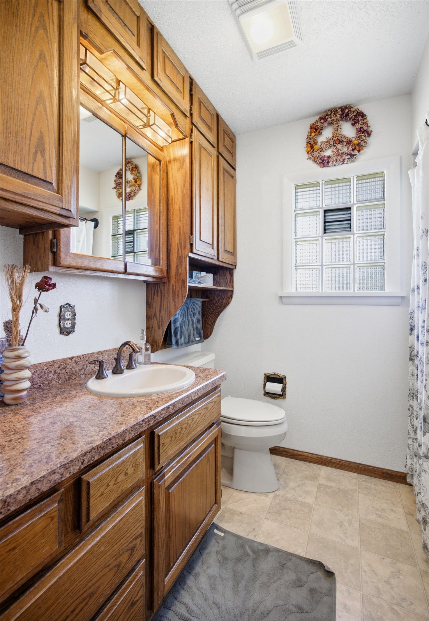 Vanity with wood-finish cabinetry, integrated sink, and laminate countertop
