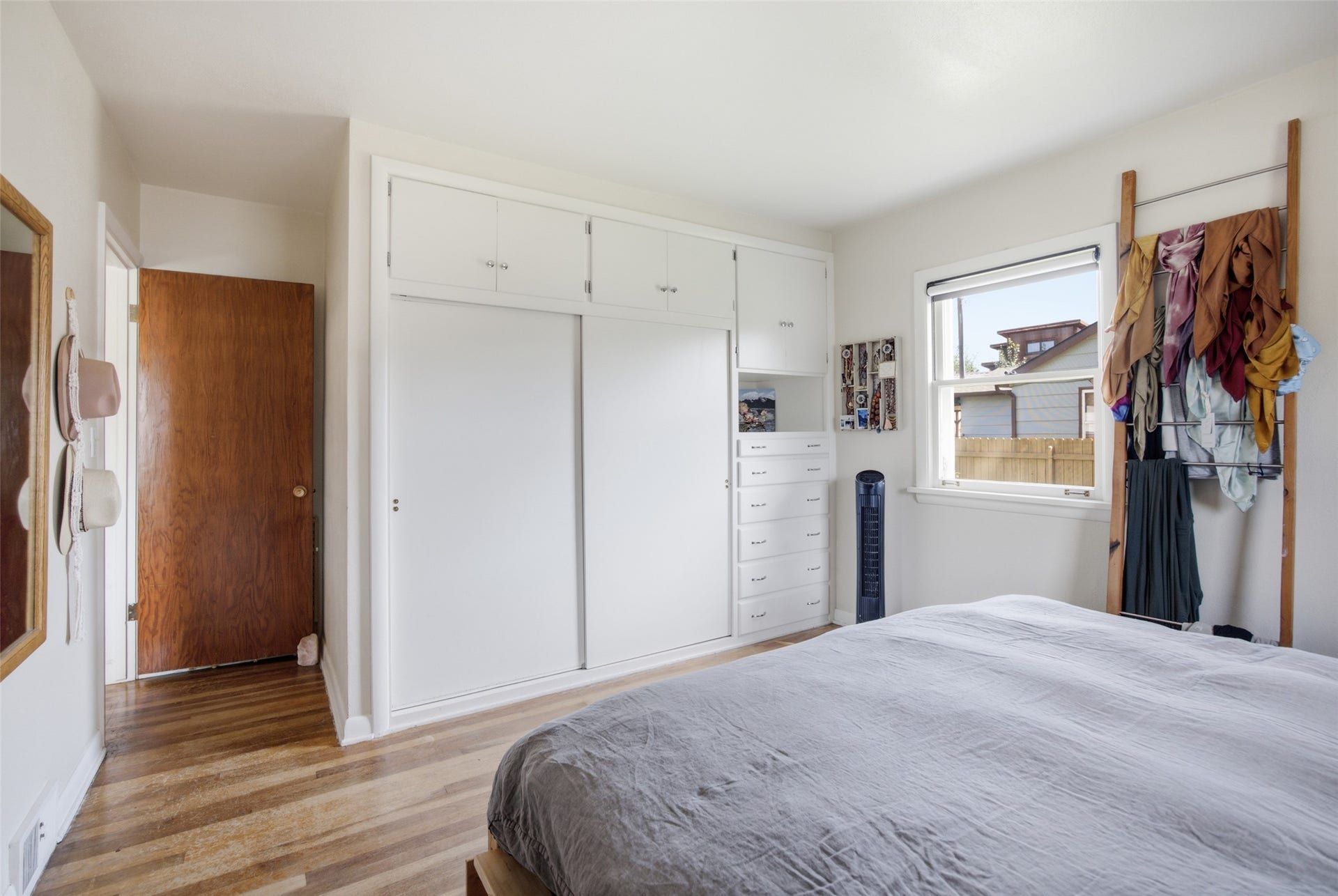 Hardwood-style flooring throughout, white painted walls, and a built-in wardrobe with sliding doors and cabinet storage