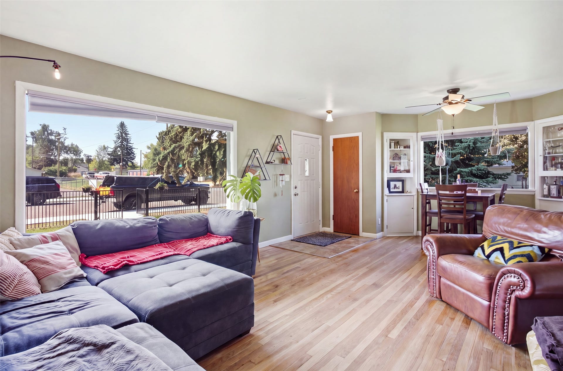 Hardwood flooring, expansive window, ceiling fan, built-in cabinetry, and a solid wood entry door