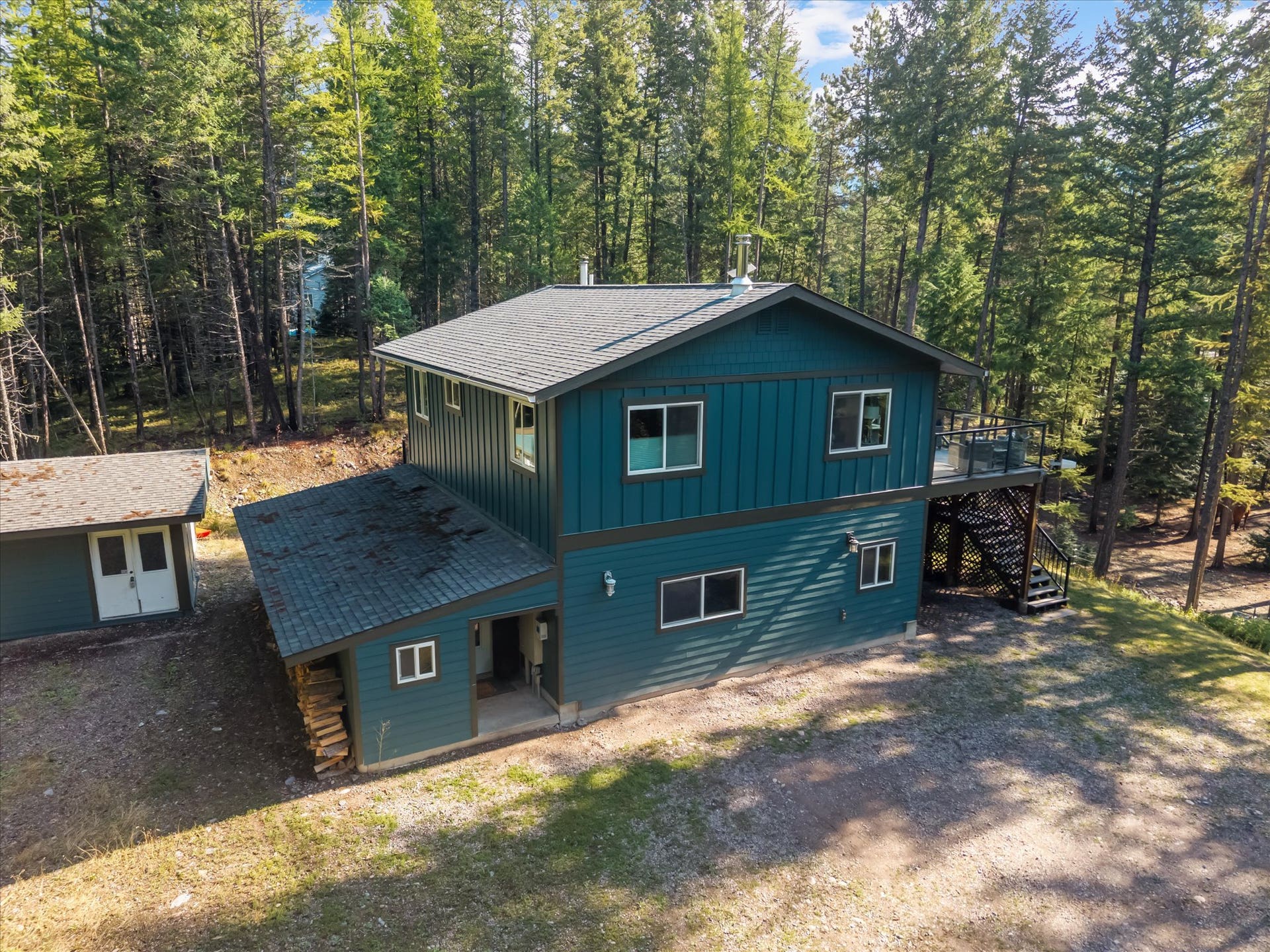 You'll love the newly painted exterior of this home that serves as a central hub for outdoor living. This view perfectly captures the secluded nature of the property, showing the home situated privately on 4.79 acres and illustrating the seamless connection between the interior and the stunning Montana landscape.