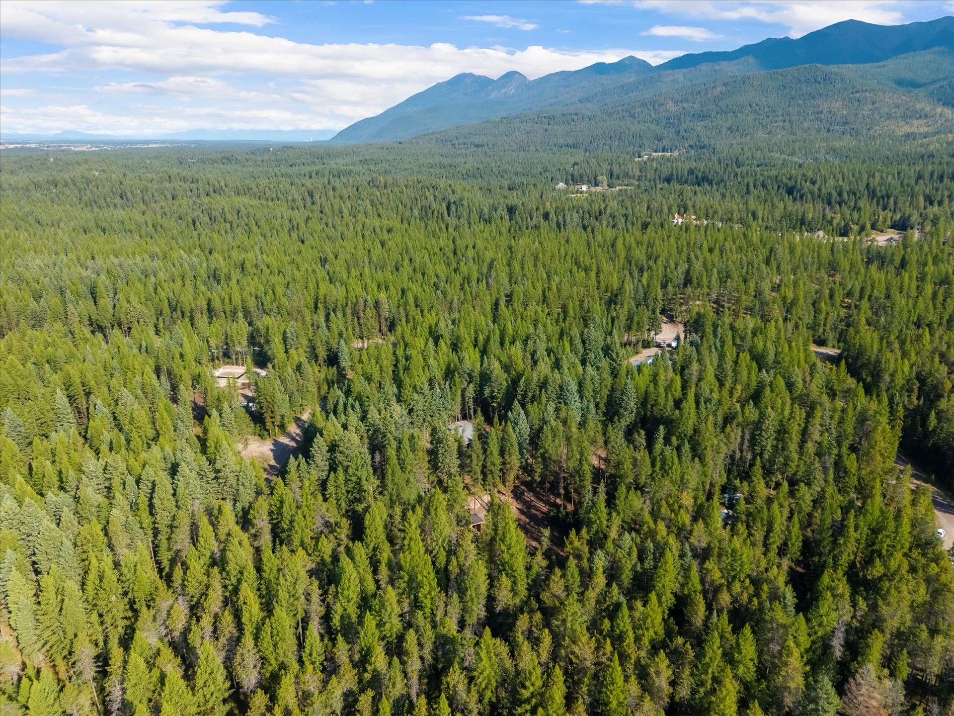 An outdoor enthusiast's paradise: Aerial view highlighting the private 4.79-acre property positioned directly along the Foothills Road corridor. Step out your front door to immediate access for summer hiking, mountain biking, and horseback riding, or explore nearby winter trails perfect for cross-country skiing and snowshoeing throughout the Flathead Valley.