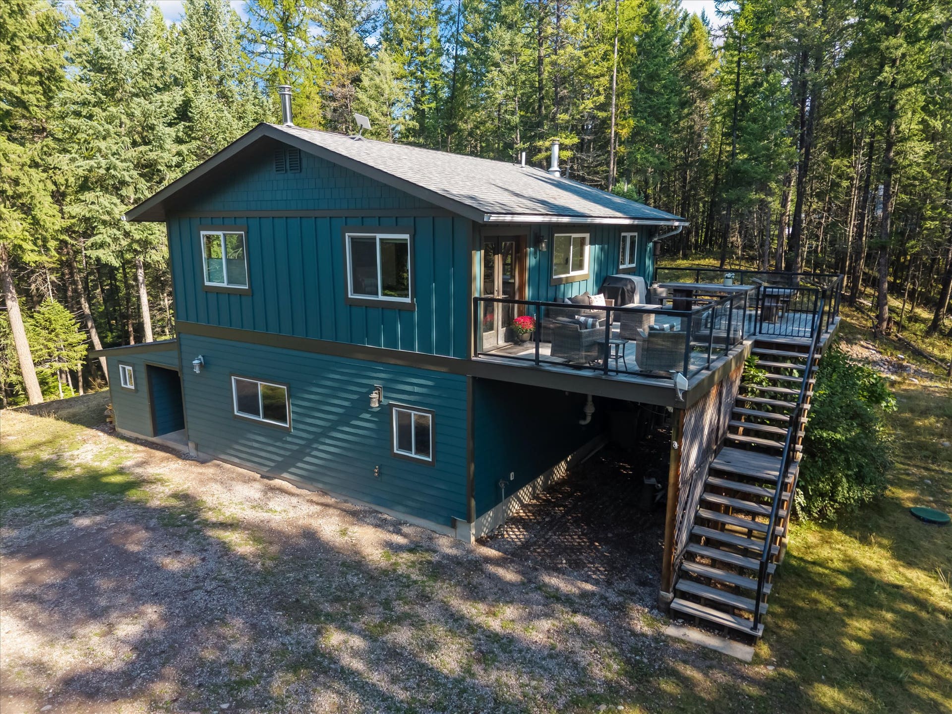 You'll love the newly painted exterior of this home that serves as a central hub for outdoor living. This view perfectly captures the secluded nature of the property, showing the home situated privately on 4.79 acres and illustrating the seamless connection between the interior and the stunning Montana landscape.