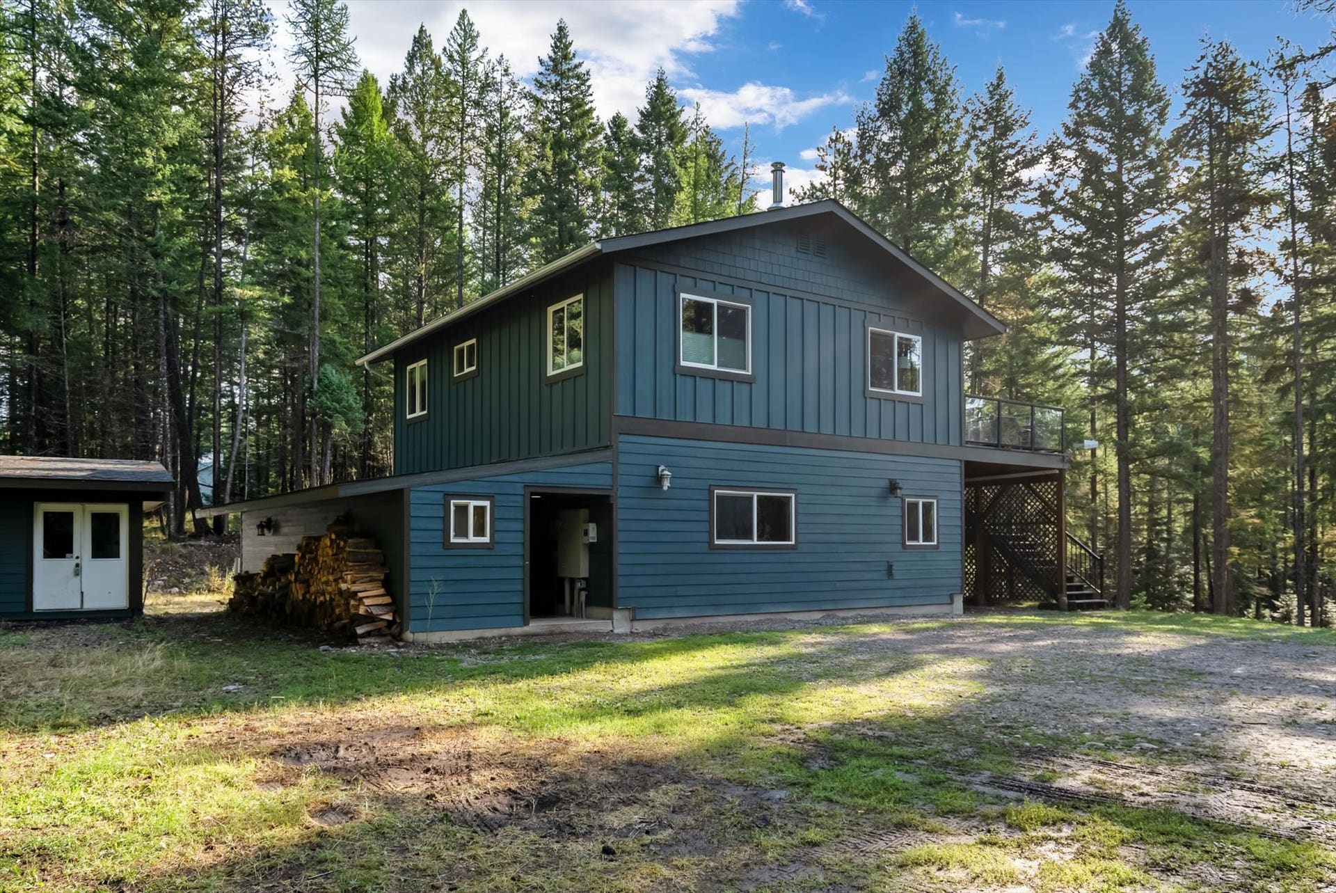 You'll love the newly painted exterior of this home that serves as a central hub for outdoor living. This view perfectly captures the secluded nature of the property, showing the home situated privately on 4.79 acres and illustrating the seamless connection between the interior and the stunning Montana landscape.