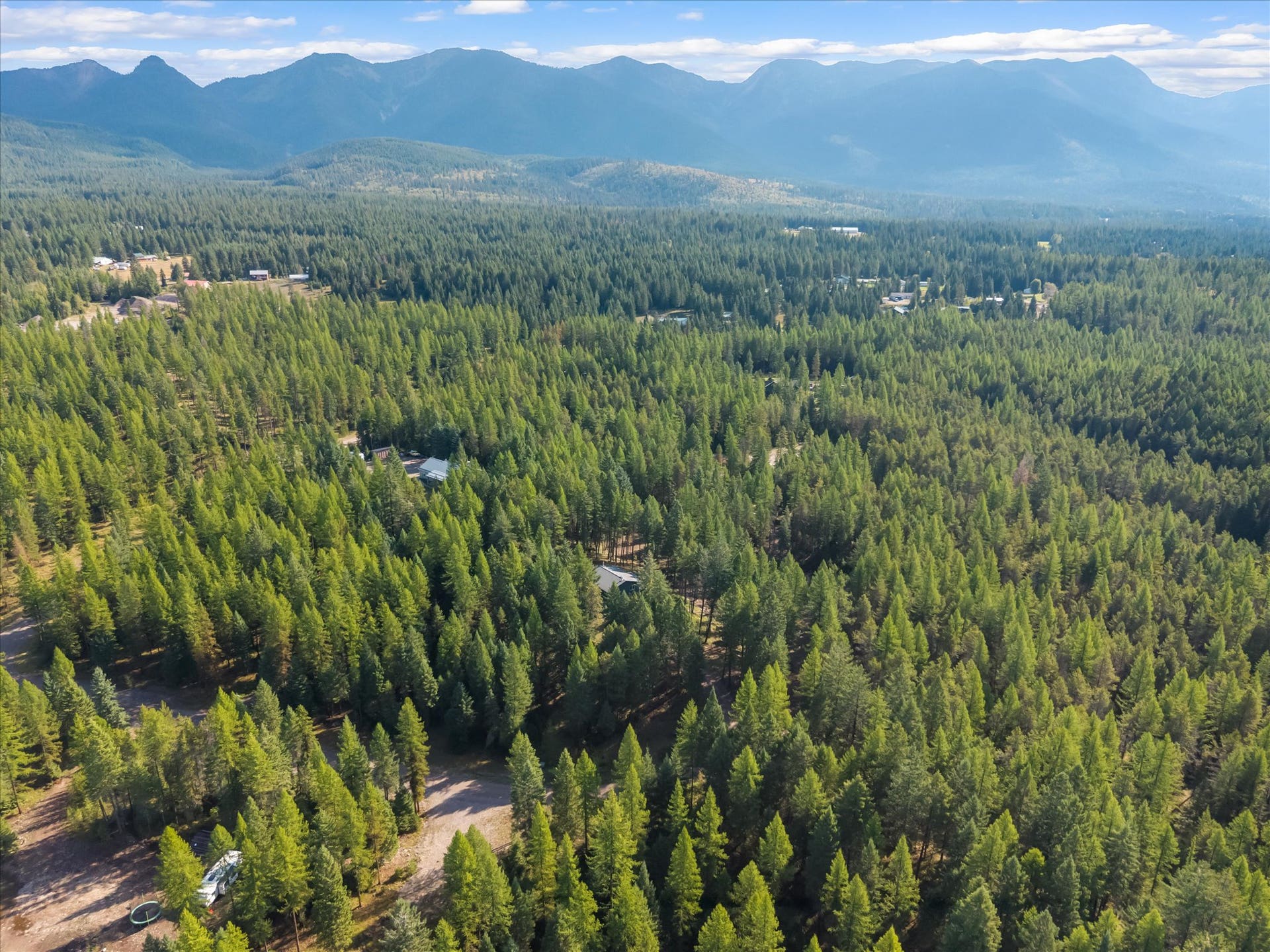 An outdoor enthusiast's paradise: Aerial view highlighting the private 4.79-acre property positioned directly along the Foothills Road corridor. Step out your front door to immediate access for summer hiking, mountain biking, and horseback riding, or explore nearby winter trails perfect for cross-country skiing and snowshoeing throughout the Flathead Valley.