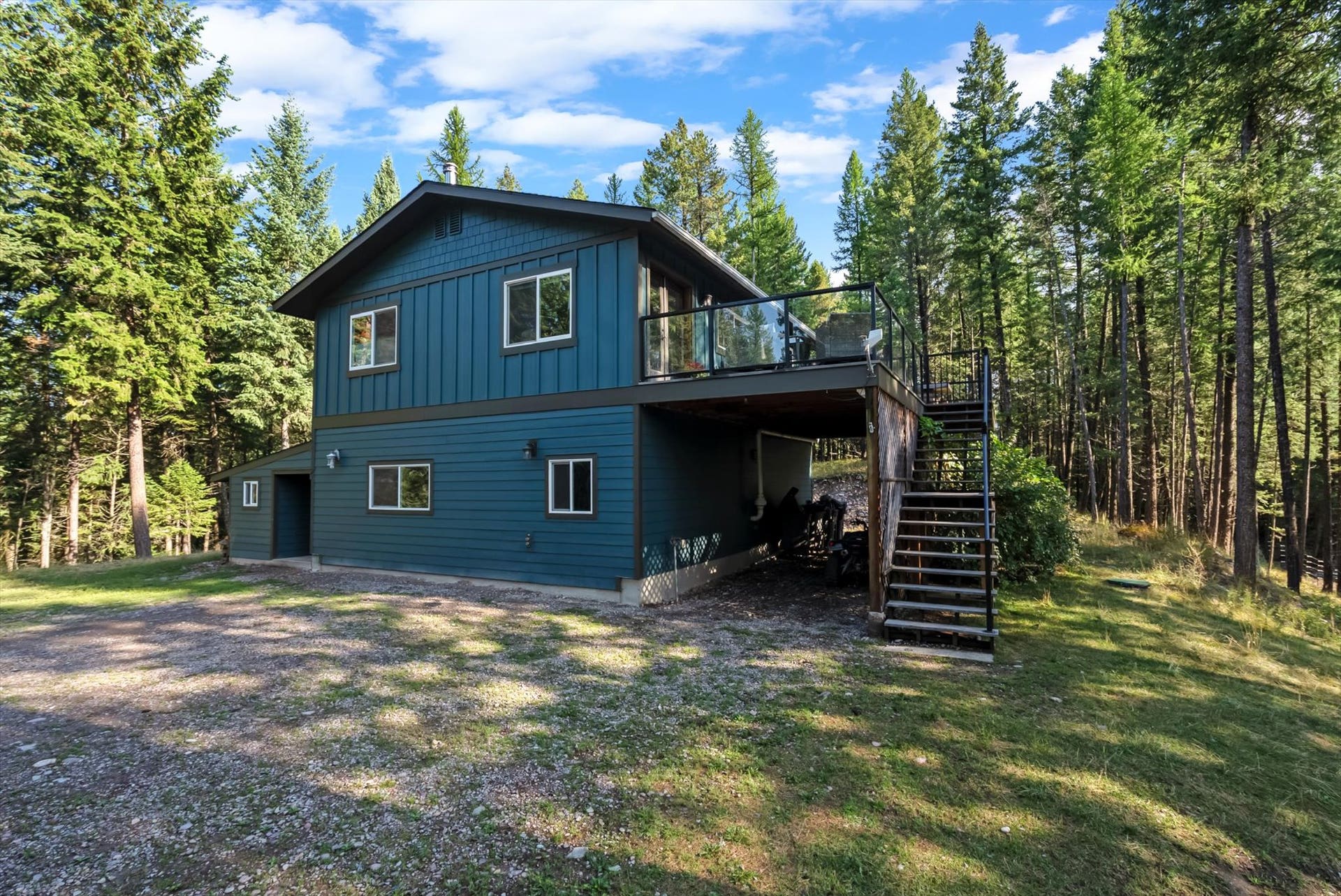 You'll love the newly painted exterior of this home that serves as a central hub for outdoor living. This view perfectly captures the secluded nature of the property, showing the home situated privately on 4.79 acres and illustrating the seamless connection between the interior and the stunning Montana landscape.