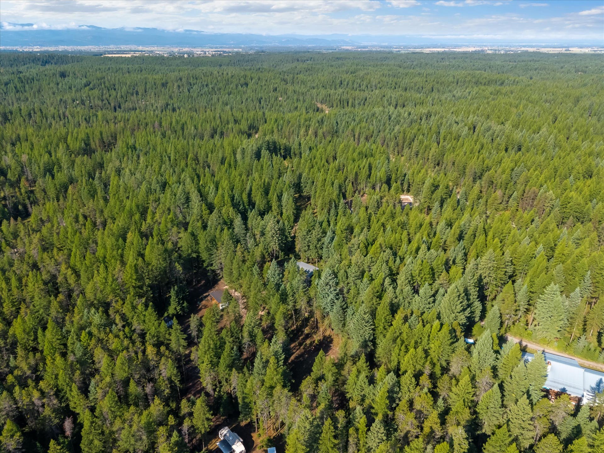 An outdoor enthusiast's paradise: Aerial view highlighting the private 4.79-acre property positioned directly along the Foothills Road corridor. Step out your front door to immediate access for summer hiking, mountain biking, and horseback riding, or explore nearby winter trails perfect for cross-country skiing and snowshoeing throughout the Flathead Valley.