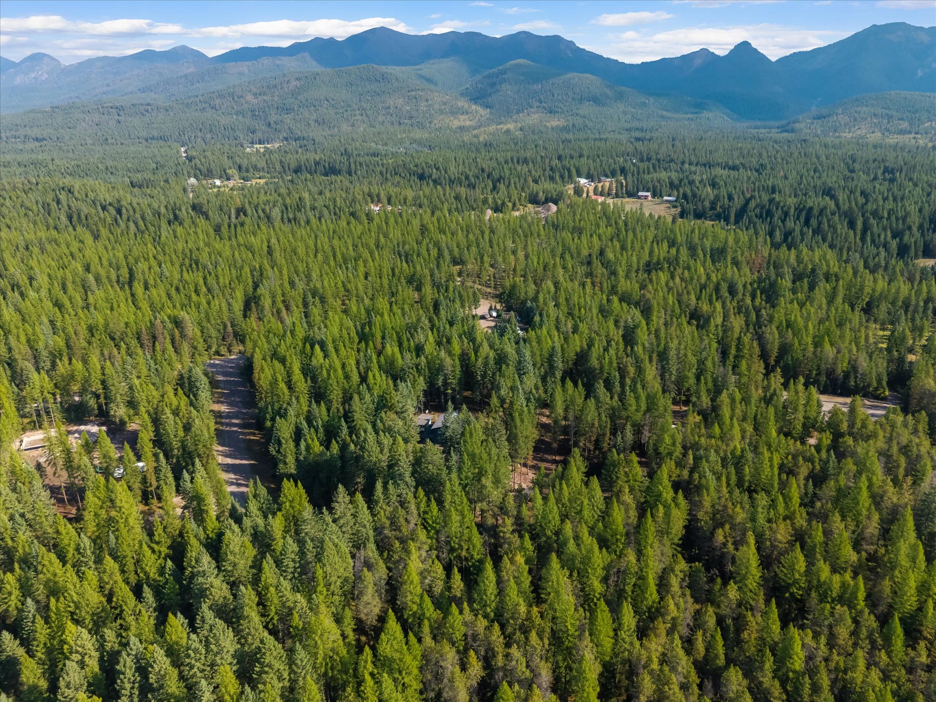 An outdoor enthusiast's paradise: Aerial view highlighting the private 4.79-acre property positioned directly along the Foothills Road corridor. Step out your front door to immediate access for summer hiking, mountain biking, and horseback riding, or explore nearby winter trails perfect for cross-country skiing and snowshoeing throughout the Flathead Valley.