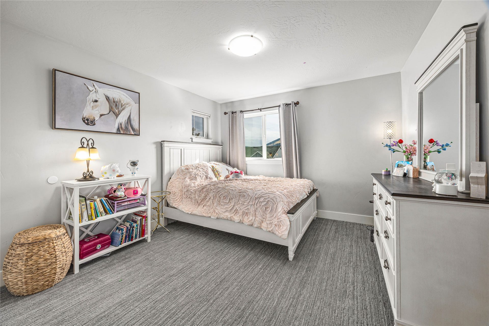 White shaker-style bed frame, durable gray carpet flooring, window with natural light, modern ceiling light fixture, and white painted walls