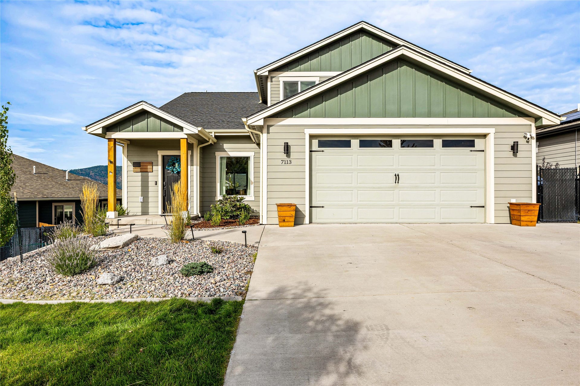 Exterior featuring neutral siding with green gables, an attached two-car garage, and a concrete driveway