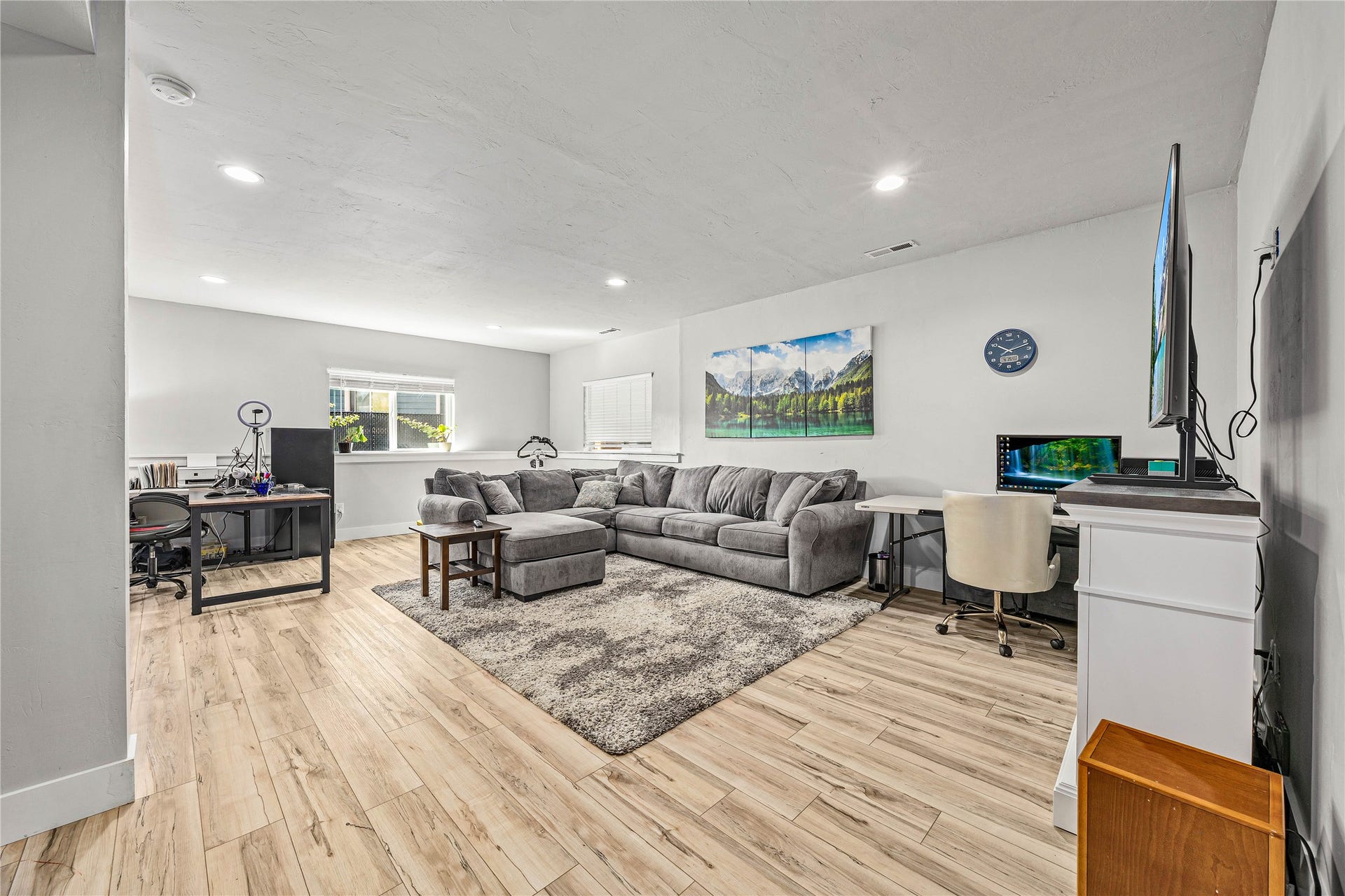 Spacious room featuring light wood-finish flooring, recessed lighting, and multiple windows