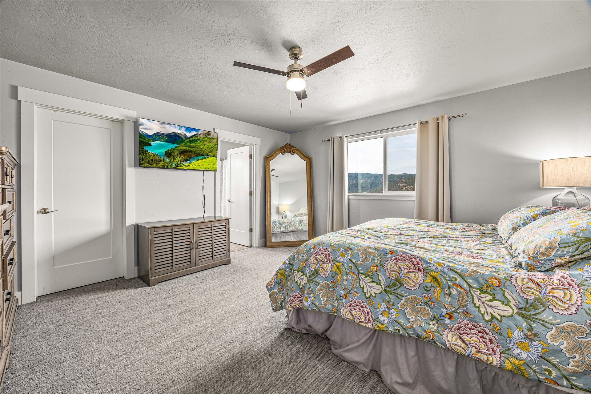 Wall-mounted ceiling fan, light gray wall color, two panel interior doors with contemporary trim, light-colored carpeting, and a large window