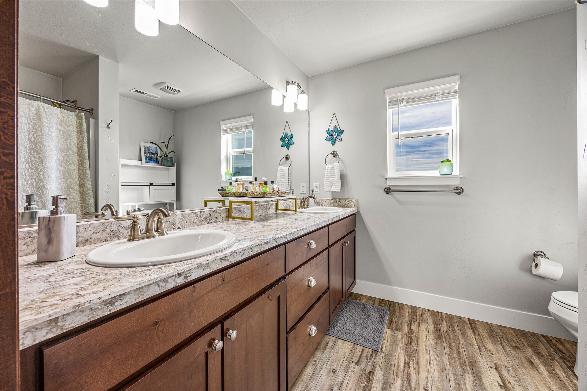 Dual vanity with wood-finish cabinetry, light-toned countertop, and undermount sinks
