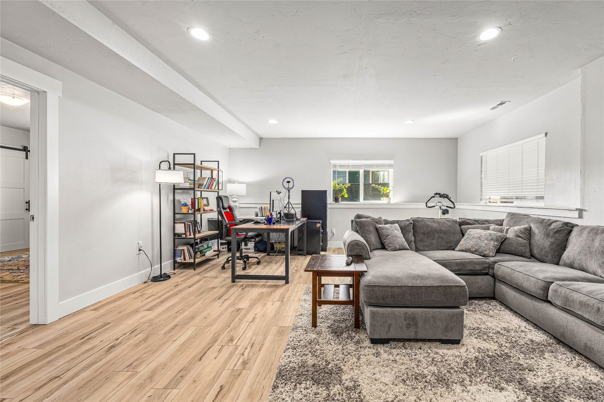Recessed ceiling lighting, wood-finish flooring, and multiple windows with horizontal blinds