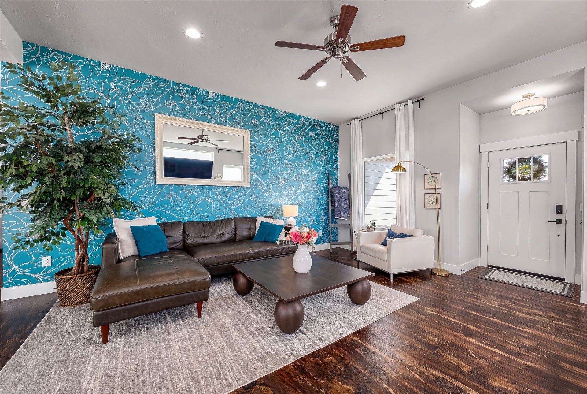 Hardwood-finish flooring, recessed lighting, ceiling fan, decorative accent wall, and built-in entry door with frosted glass panel