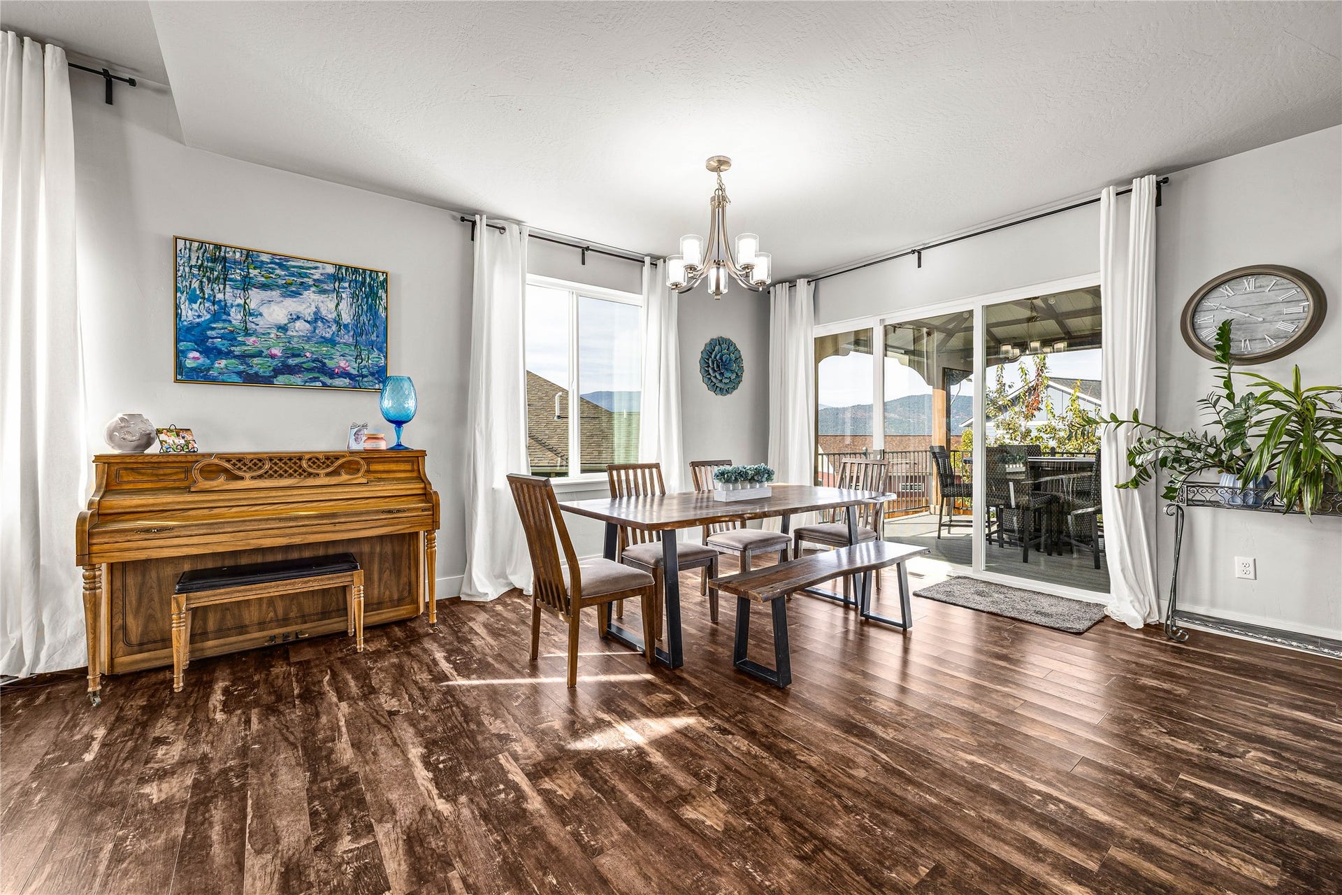 Wood-finish flooring, sliding glass door access to outdoor living, chandelier lighting, and abundant natural light