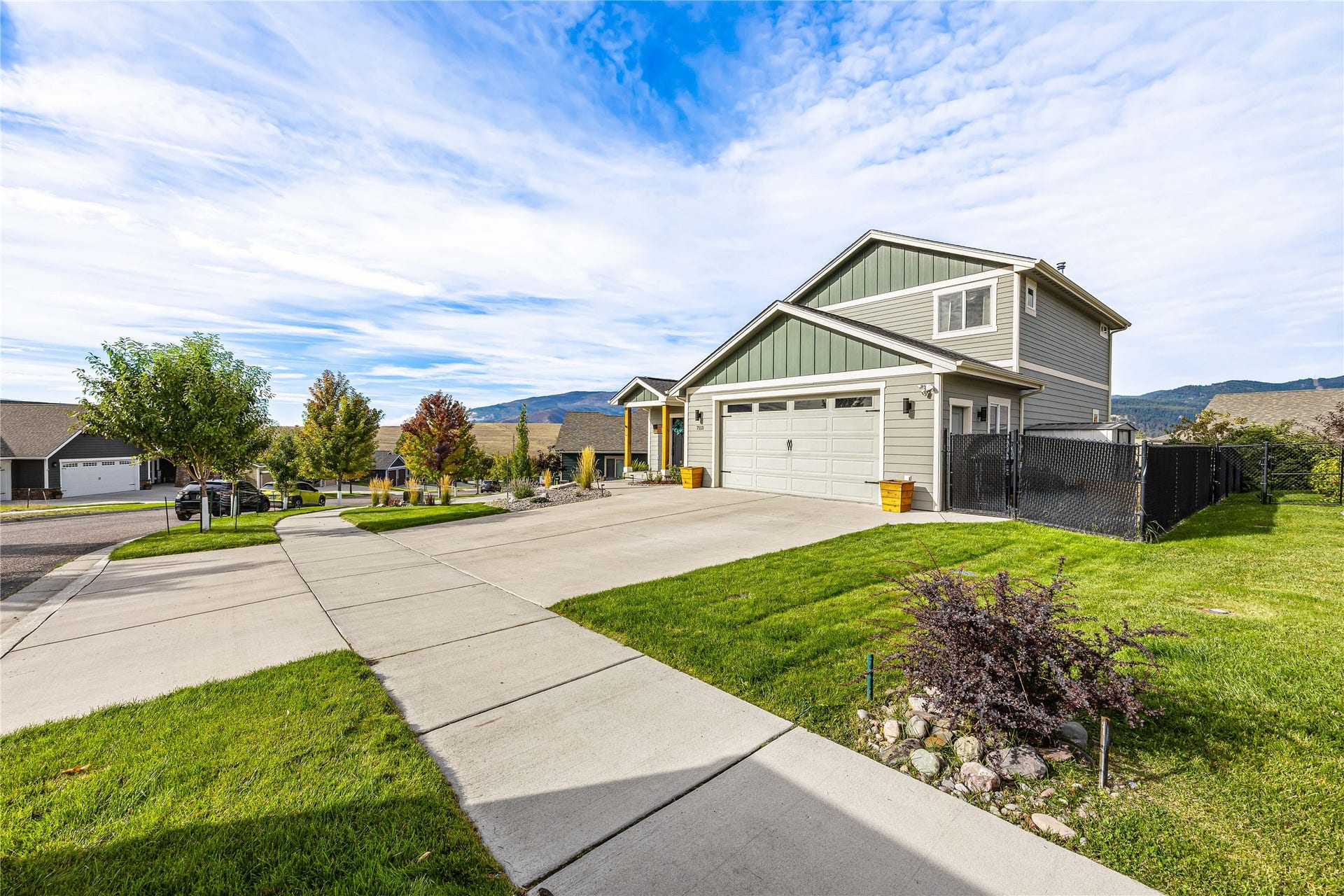 Two-story residence with a two-car garage, gray siding, and green gables