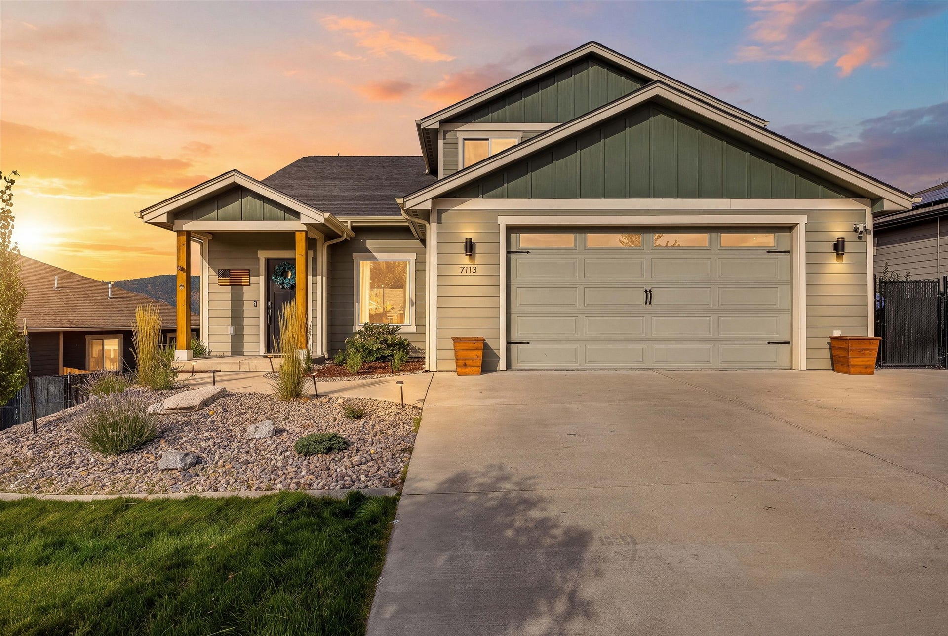Contemporary-style home featuring a two-car garage, covered entry porch with wood posts, and a low-maintenance xeriscape front yard