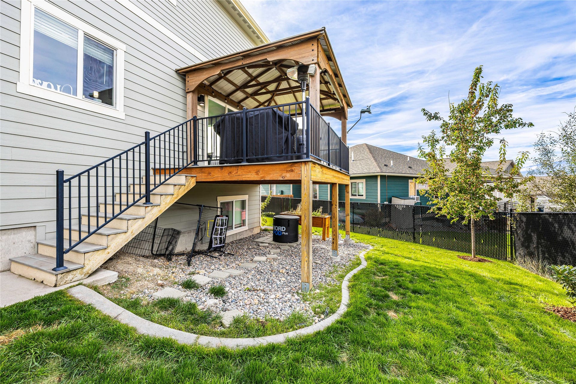Covered outdoor deck with decorative wood railing and black metal balusters