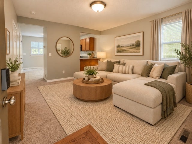 Carpeted living area with light-toned walls, an overhead ceiling light fixture, and window with blinds