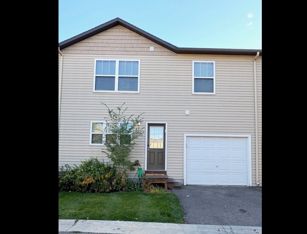 Light-toned siding exterior with a peaked roofline, front entry door, and integrated single-car garage
