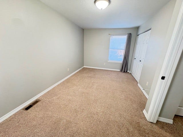 Neutral wall color, carpeted flooring, white trim, window with privacy covering, and a bi-fold closet
