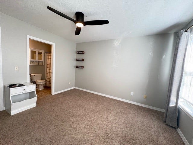 Carpeted room with a ceiling fan