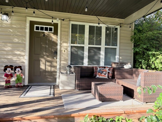 Inviting covered porch with wood decking, multiple windows, and a panel door with transom detail