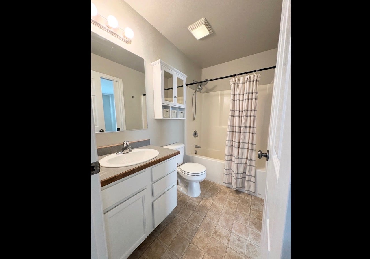 White vanity with an integrated sink, large wall mirror, and overhead vanity lighting