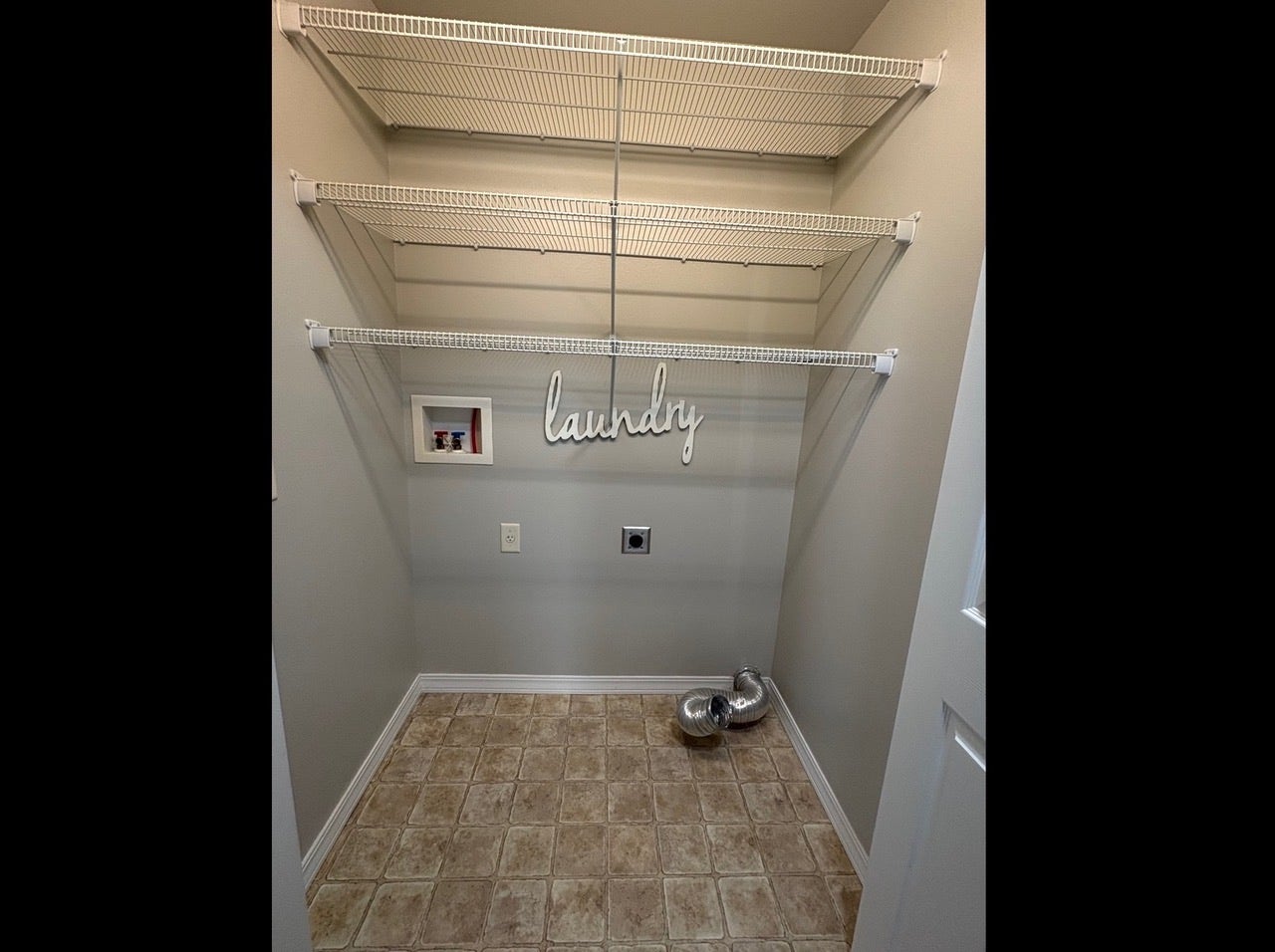 Utility area with tiled flooring, neutral wall paint, and multiple wire shelving units