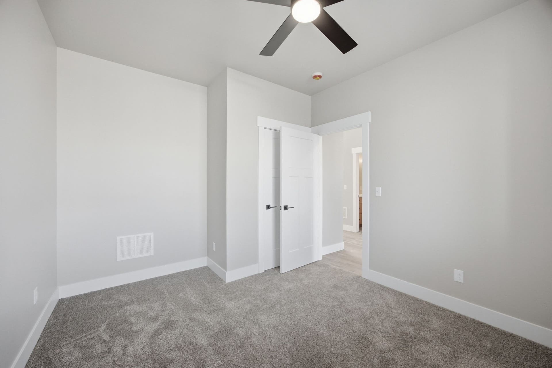 Plush carpet flooring, ceiling fan, white interior doors, and neutral wall tones