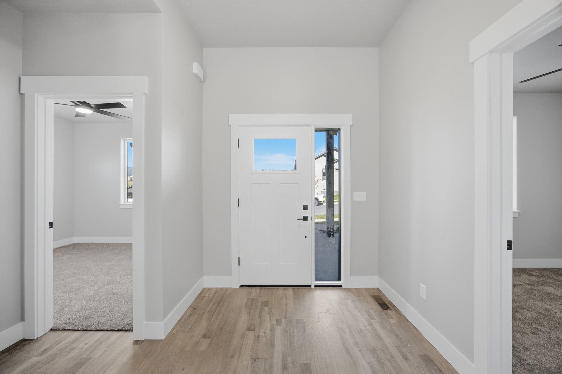 Entryway featuring wood-finish flooring, white trim, and a white entry door with a clear glass sidelight