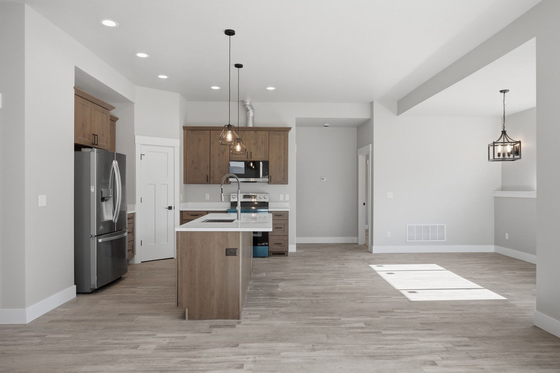 Kitchen featuring wood-finish cabinetry, stainless steel appliances, recessed lighting, and a center island with pendant lighting