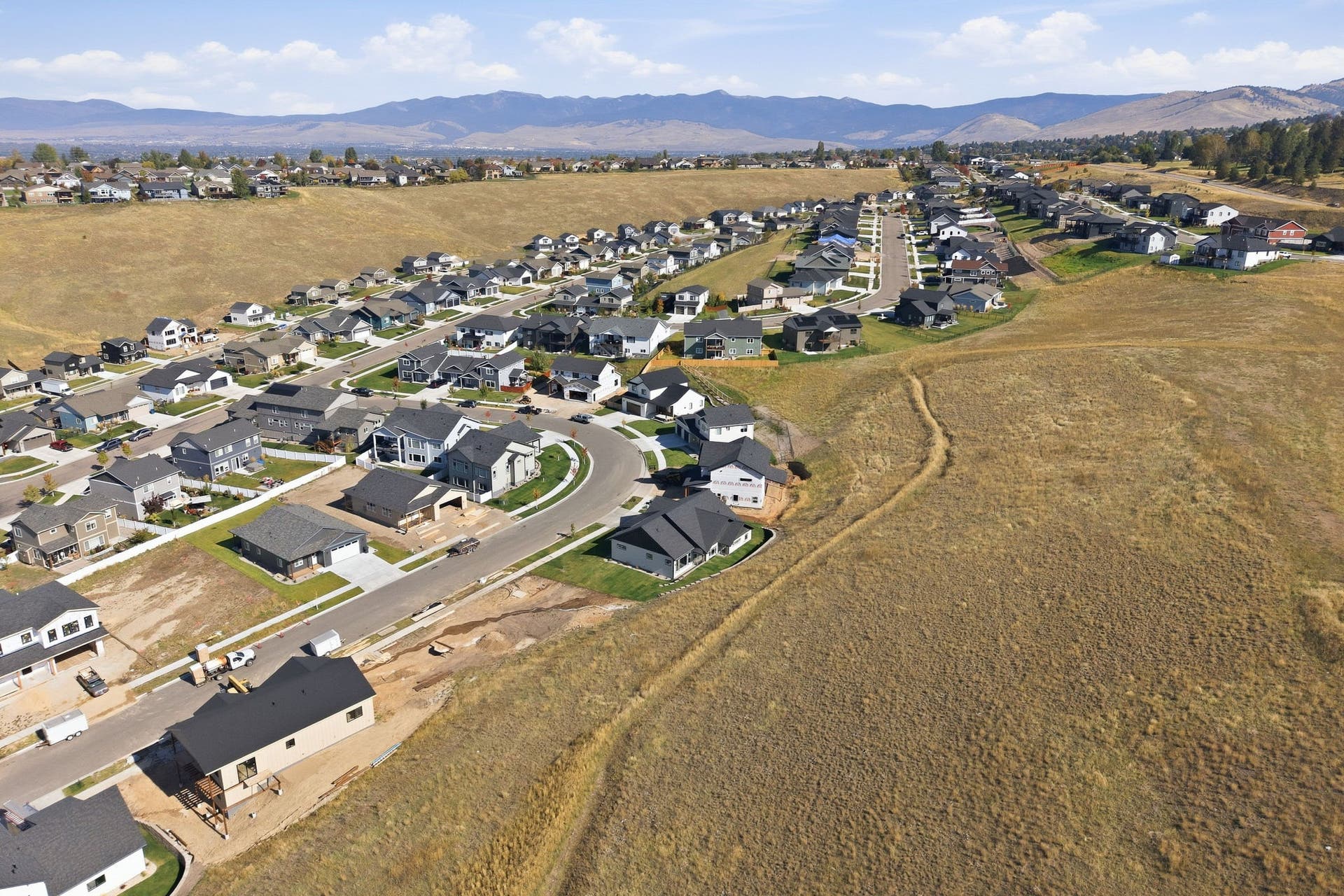 Established residential neighborhood with a curved street layout, surrounded by undeveloped land