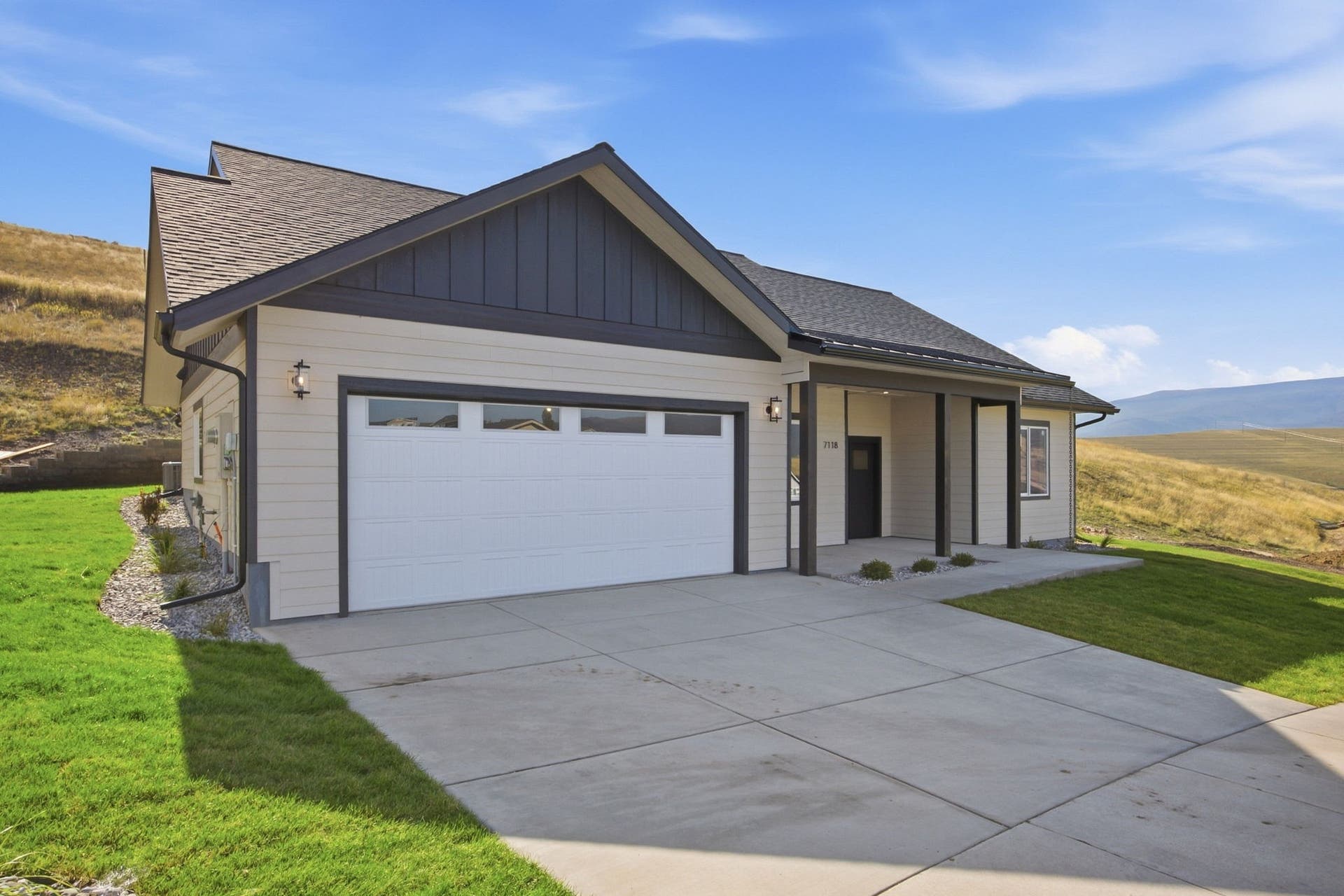 Exterior featuring horizontal siding, dark trim, an attached garage, a covered entry, and a concrete driveway