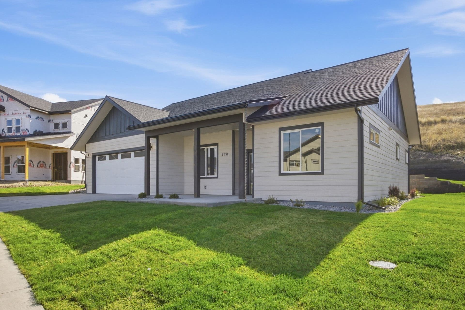 Contemporary exterior with light-colored siding, dark trim accents, attached garage, and a manicured lawn