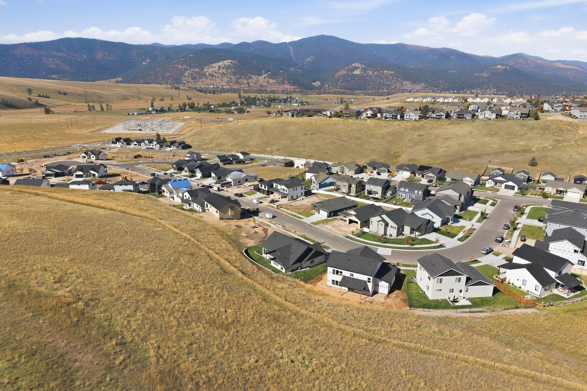 Mountain backdrop with extensive residential development, featuring multiple residential structures and paved streets