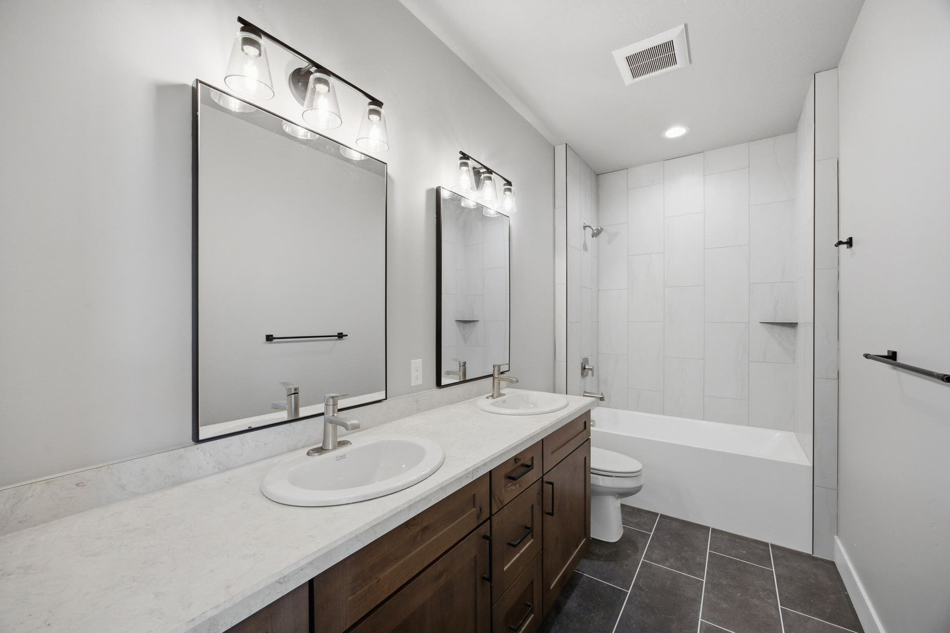 Dual vanity with undermount sinks, wood-finish cabinetry, and light-toned countertops