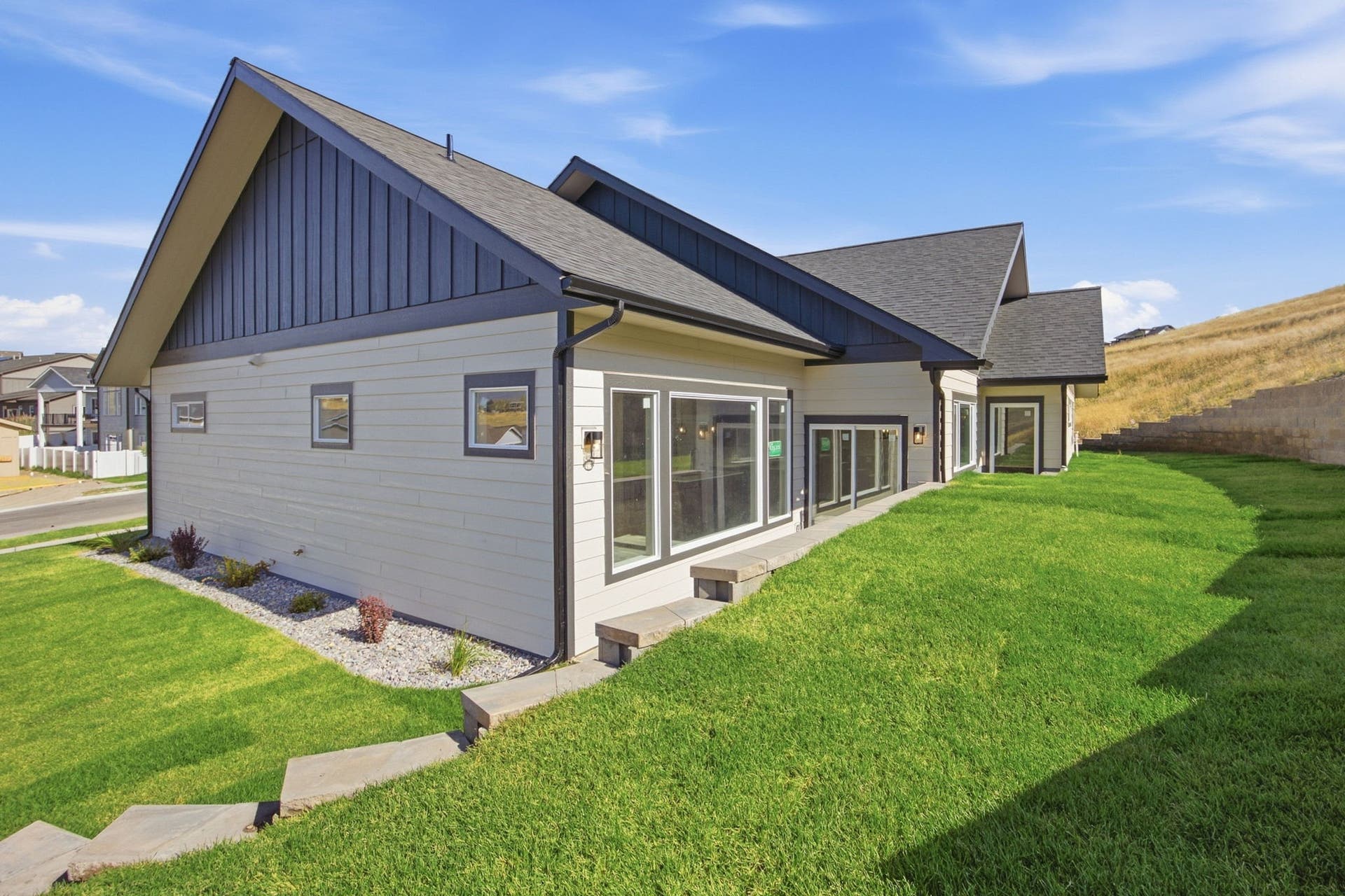 Modern exterior siding with board and batten accents, multiple large windows, and a multi-pitch roofline
