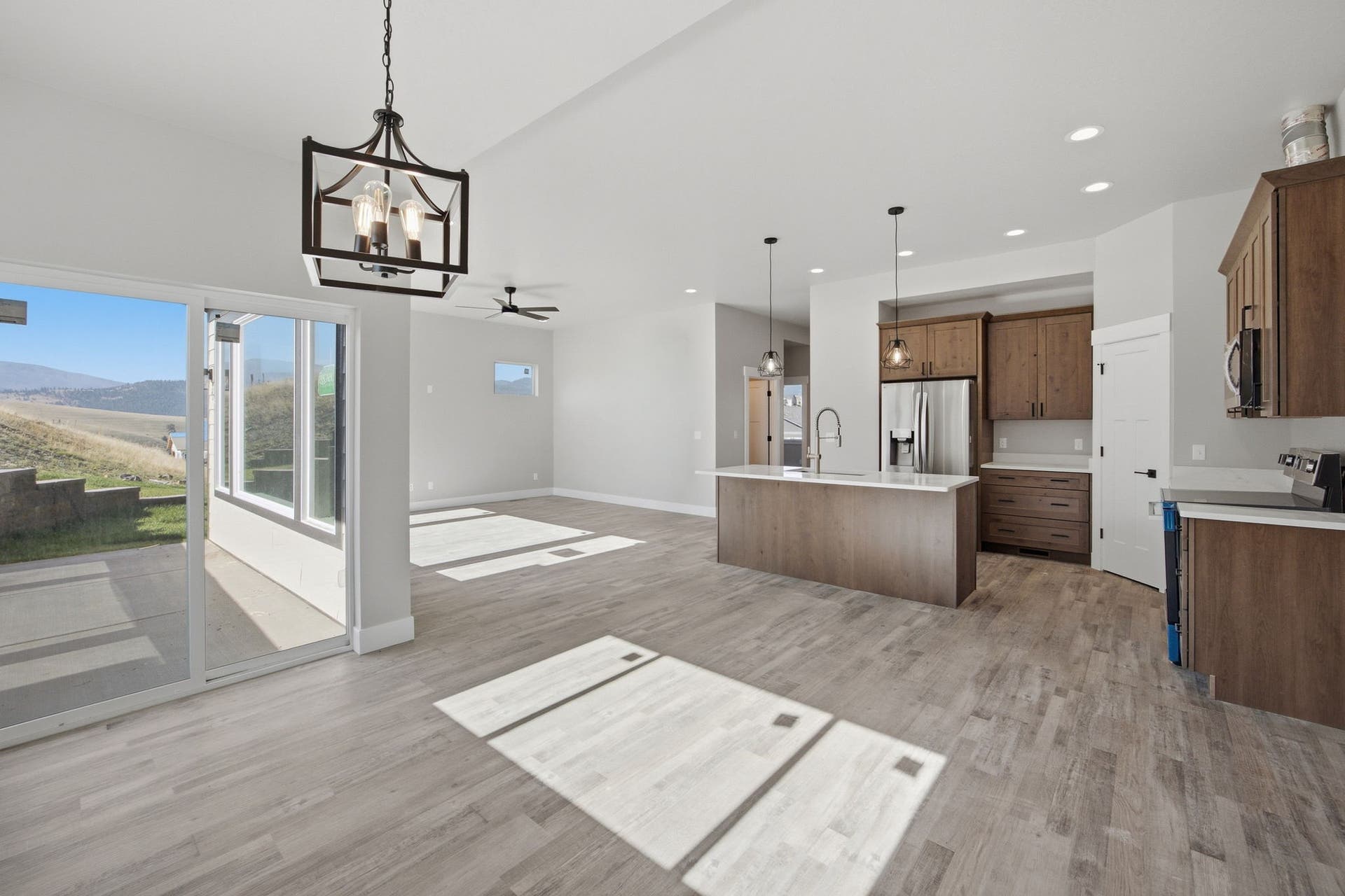 Open-concept living area with wood-finish flooring, a kitchen island, pendant lighting, and sliding glass doors