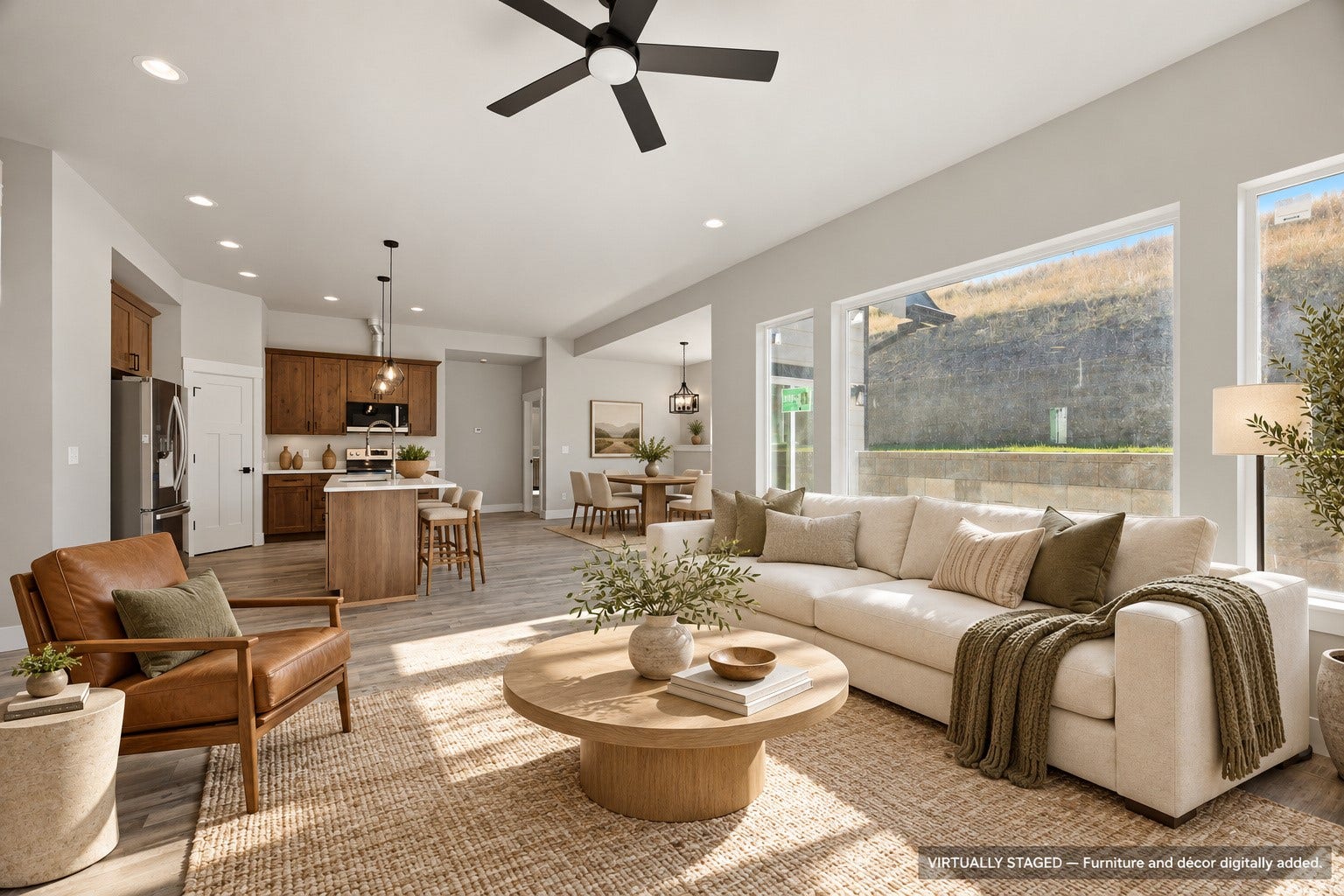 Open-concept living area featuring a kitchen with wood cabinetry and an island, recessed lighting, a ceiling fan, and large windows
