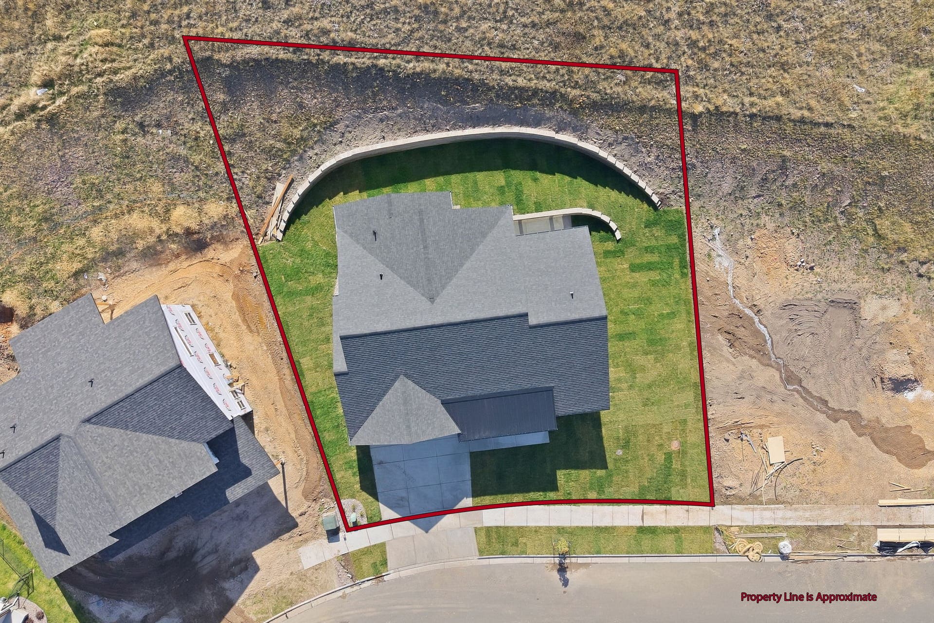 Manicured lawn surrounding the residence, concrete retaining wall, and paved street frontage