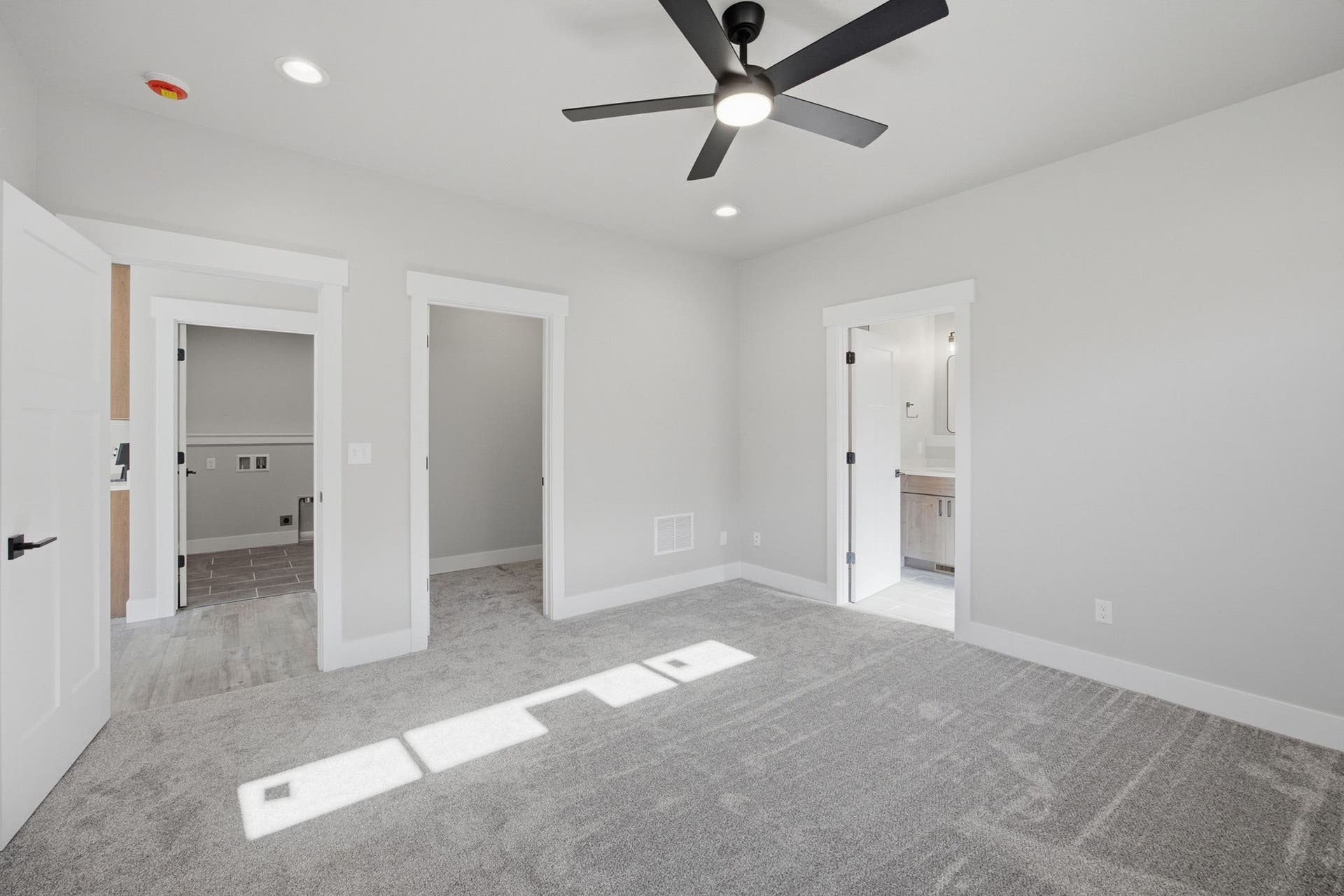 Plush grey carpeting, recessed lighting, and a contemporary ceiling fan with integrated lighting