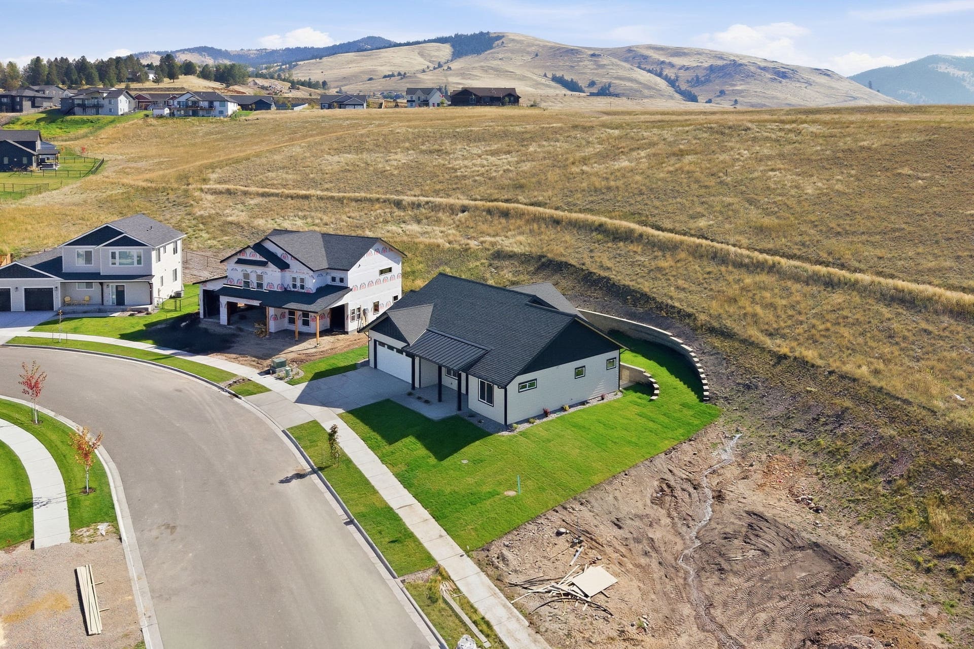 Newly constructed residence featuring a dark shingle roof, white exterior siding, and an attached two-car garage