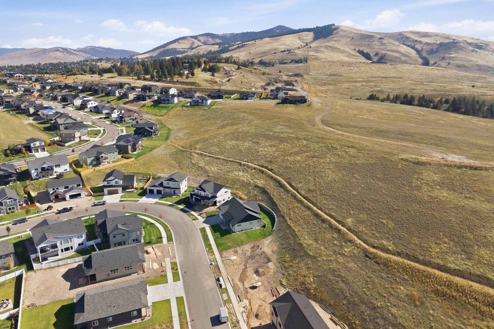 Established residential area with a curved street layout, surrounded by natural land features and distant mountains
